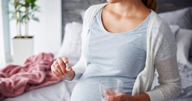 se muestra mujer embarazada sentada suplementándose con pastillas de ácido fólico